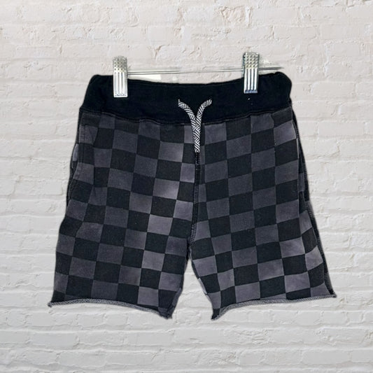 Black and grey checkered shorts with a drawstring waistband hanging on a hanger.