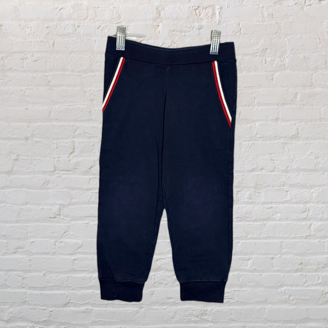 Navy blue Moncler kids' track suit with zip-up jacket and matching pants, featuring red, white, and blue trim detail on pockets.