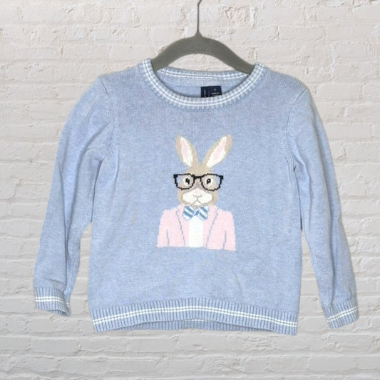 Light blue sweater with a bunny wearing glasses and a bow tie design, hanging on a hanger.