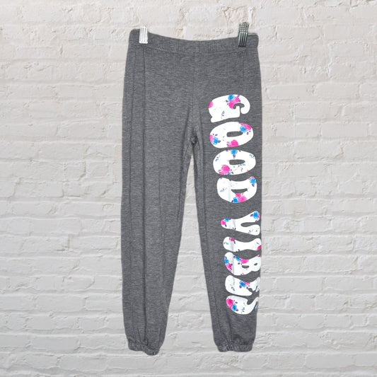 Grey sweatpants with 'Good Vibes' printed in large, colorful letters down one leg.