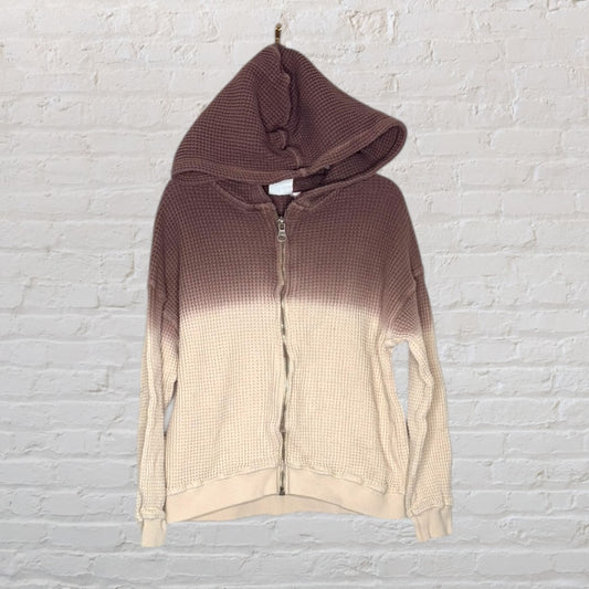 Waffle knit zip-up hoodie with ombre design in brown and beige, displayed on a white brick background.