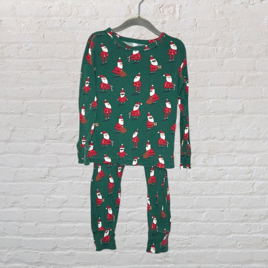 Green pajama set with Santa Claus prints, featuring a long-sleeve top and matching pants, hanging on a hanger.