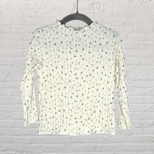 Cream ribbed long sleeve top with a small floral print and ruffled neckline, hanging on a hanger.