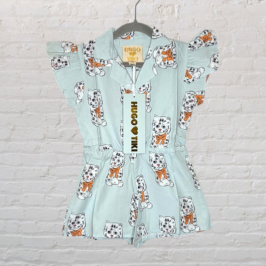 Light blue romper with cat print and ruffle sleeves by Hugo Loves Tiki, hanging on a hanger with a tag attached.