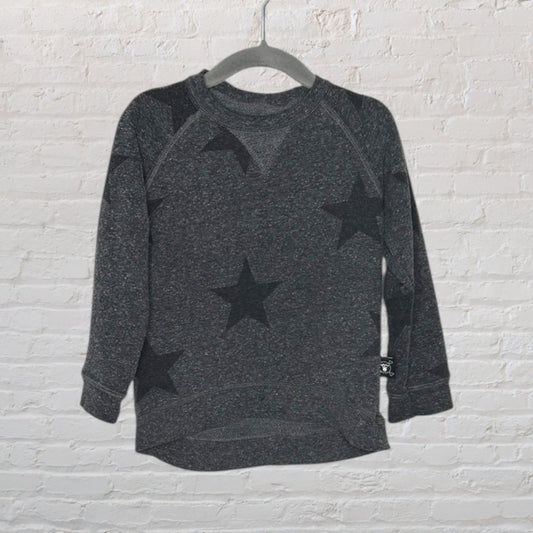 Dark heather grey sweater with large black star patterns, hanging on a grey hanger against a white brick background.