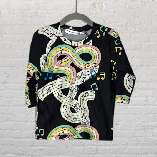 Unisex long sleeve tee with vibrant musical note pattern by Mini Rodini, displayed on a hanger.