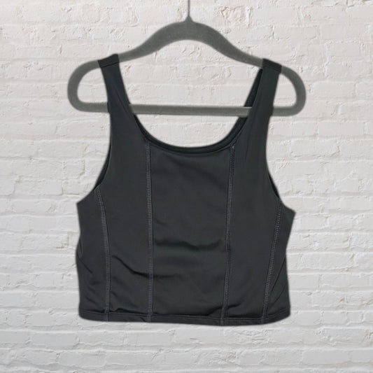 Black sport tank top with structured seams, displayed on a hanger.