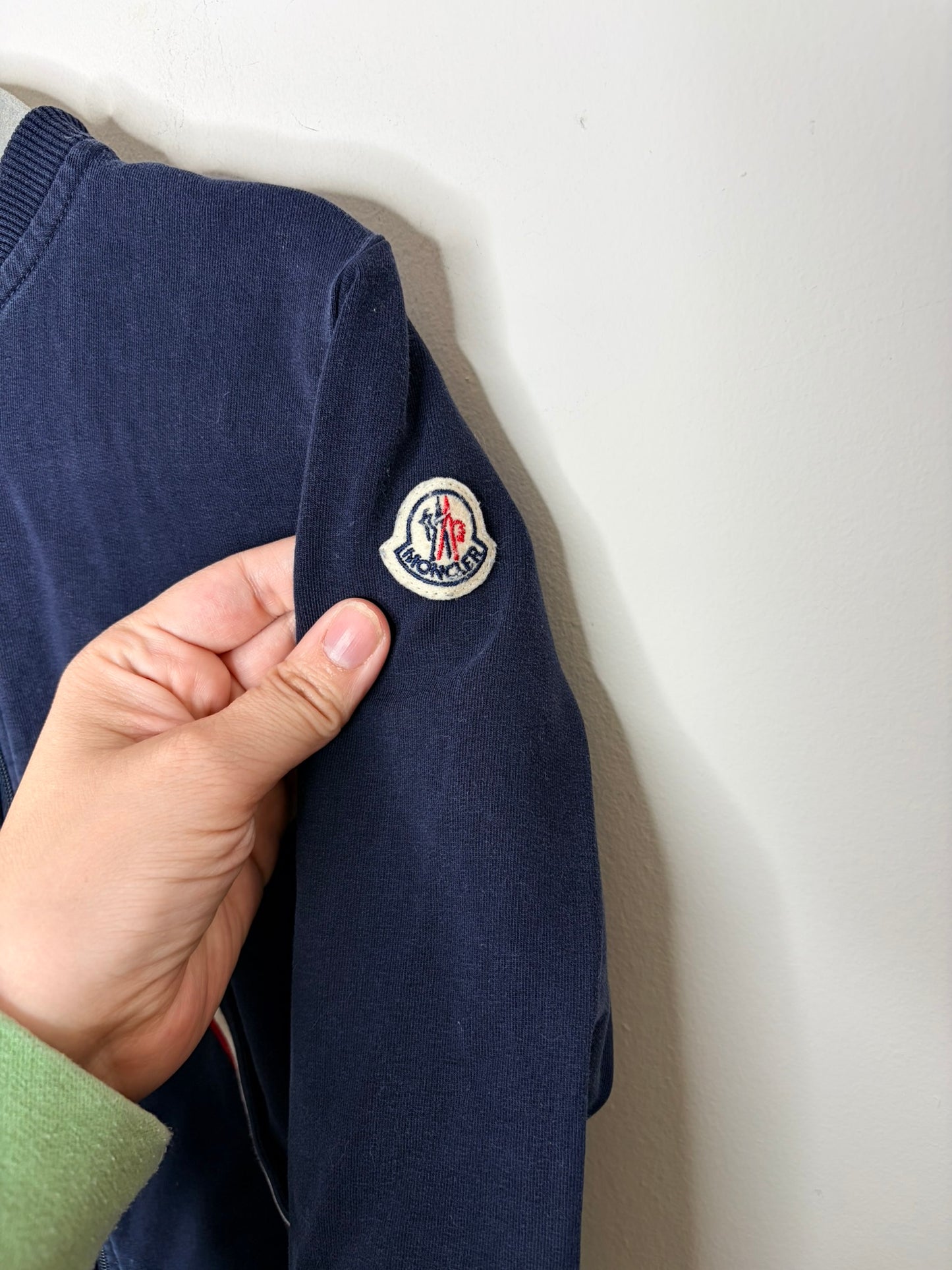 Navy blue Moncler kids' track suit with zip-up jacket and matching pants, featuring red, white, and blue trim detail on pockets.