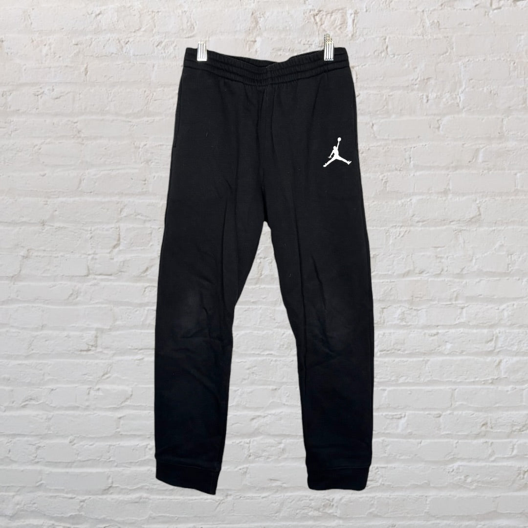 Black sweatpants with Air Jordan logo on left leg, displayed against a brick wall.