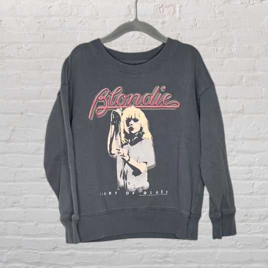 Grey sweatshirt featuring a Blondie graphic with 'Heart of Glass' text, displayed on a hanger against a white brick wall.