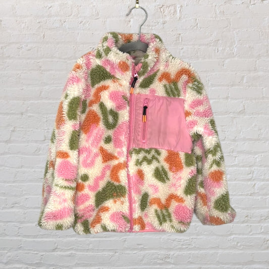 Multicolored fleece jacket with patterns in pink, green, and orange, featuring a pink pocket displayed on a hanger.