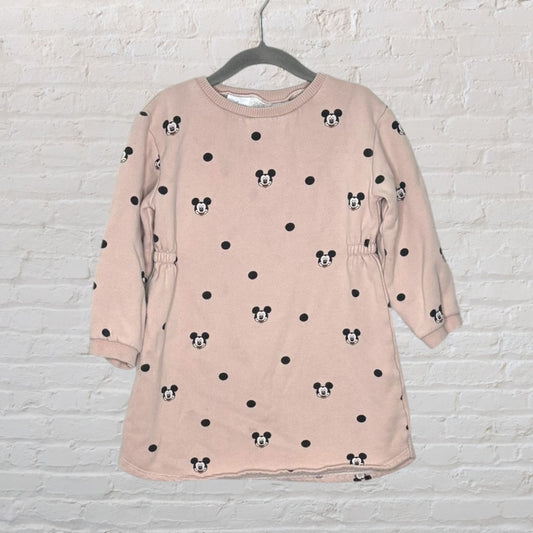 Pink sweatshirt dress with black Mickey Mouse and polka dot print, hanging on a hanger.