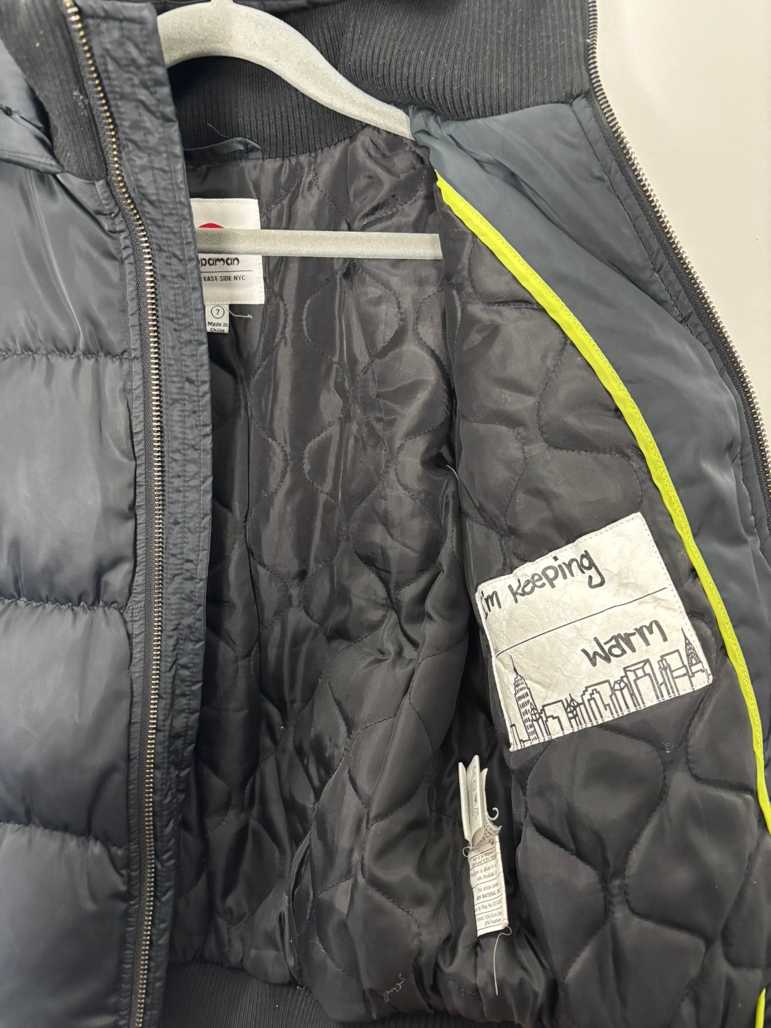 Black puffer jacket with a hood and a zip closure, featuring a small logo on the sleeve.