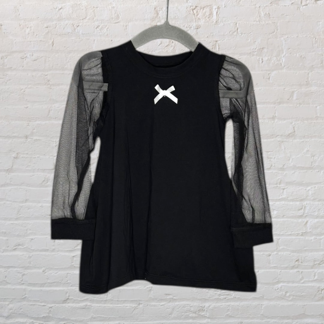 Black top with mesh sleeves and a white bow detail at the neckline, hanging on a grey hanger.
