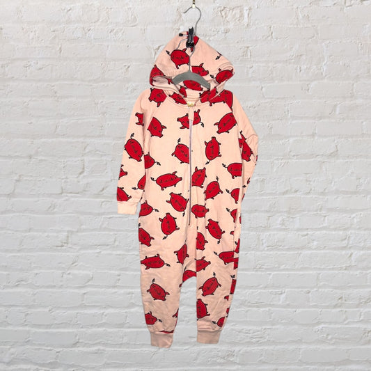 Peach-colored hooded onesie with a red pig pattern, displayed against a white brick wall.