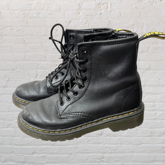 Pair of black lace-up combat boots with yellow stitching and pull tabs, showing signs of wear.