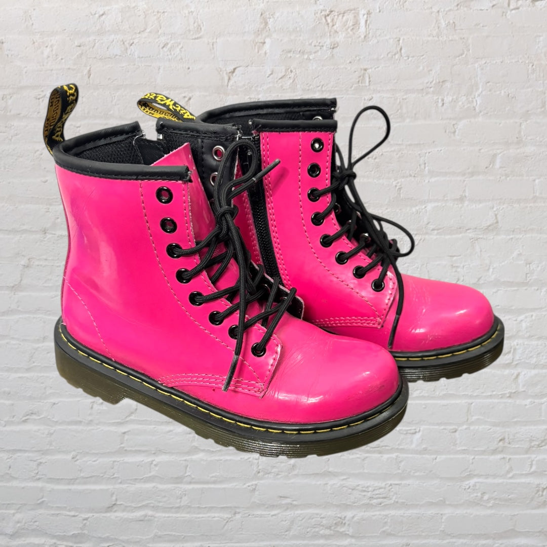 Bright pink lace-up combat boots with black laces and soles, featuring a pull tab at the back.