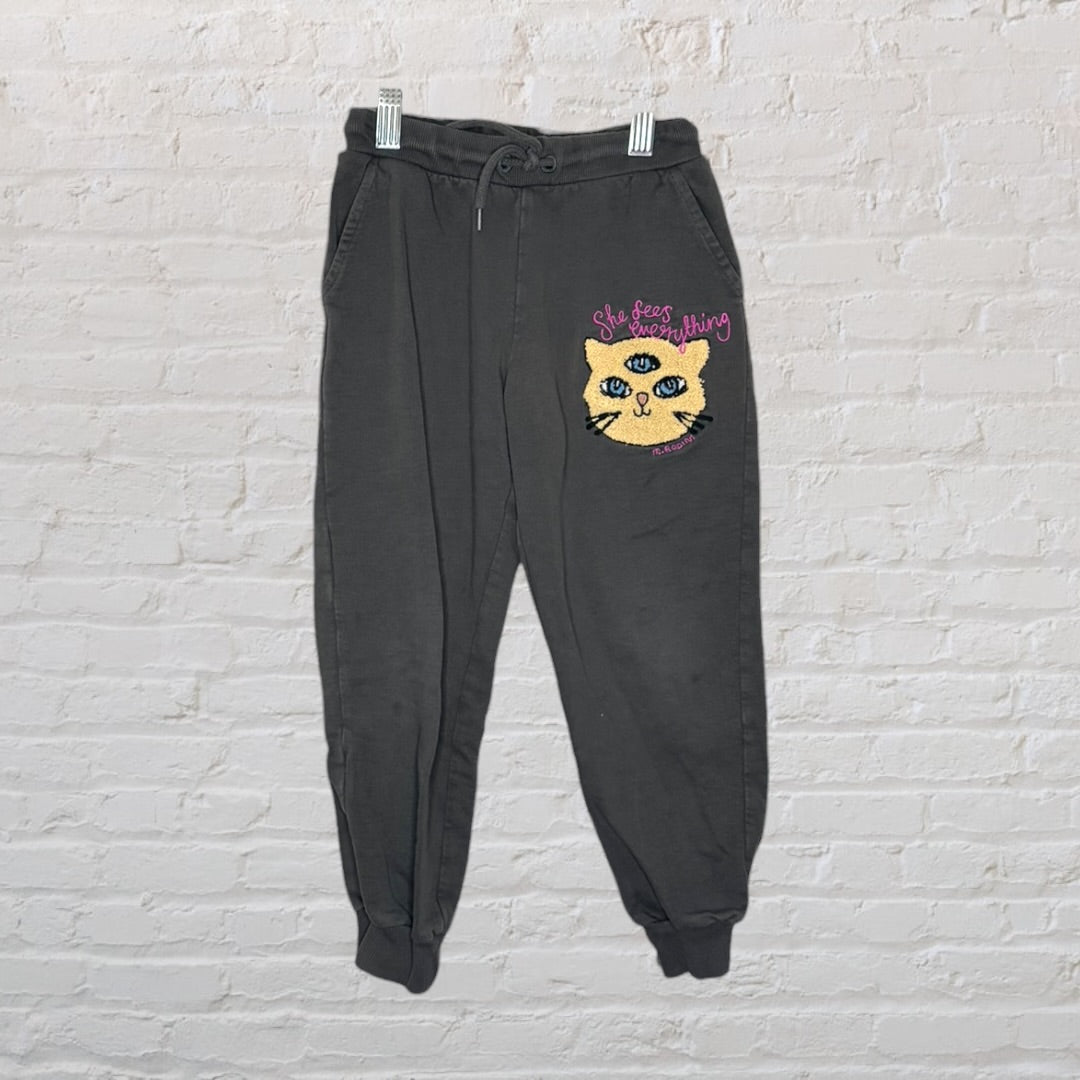 Charcoal sweatshirt and pants set featuring a cat graphic with three eyes and 'She Sees Everything' text by Mini Rodini.