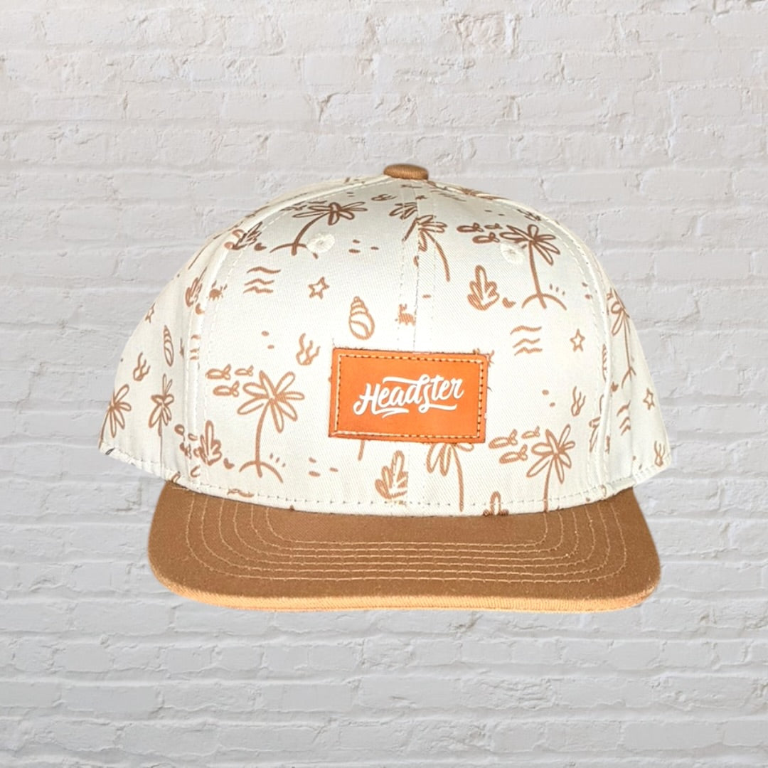 Beige and brown cap with tropical print design and Headster logo patch on front.