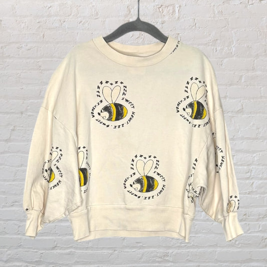 Cream-colored drop shoulder sweatshirt featuring a whimsical bee print with 'Bzzz' text pattern.