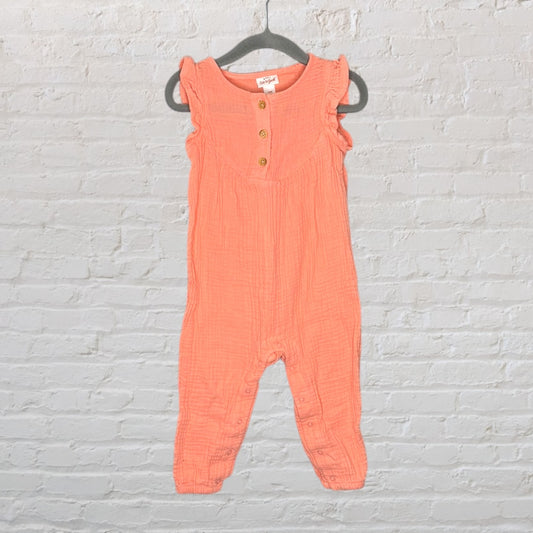 Peach-colored sleeveless romper with ruffle detail and button front, hanging on a gray hanger.