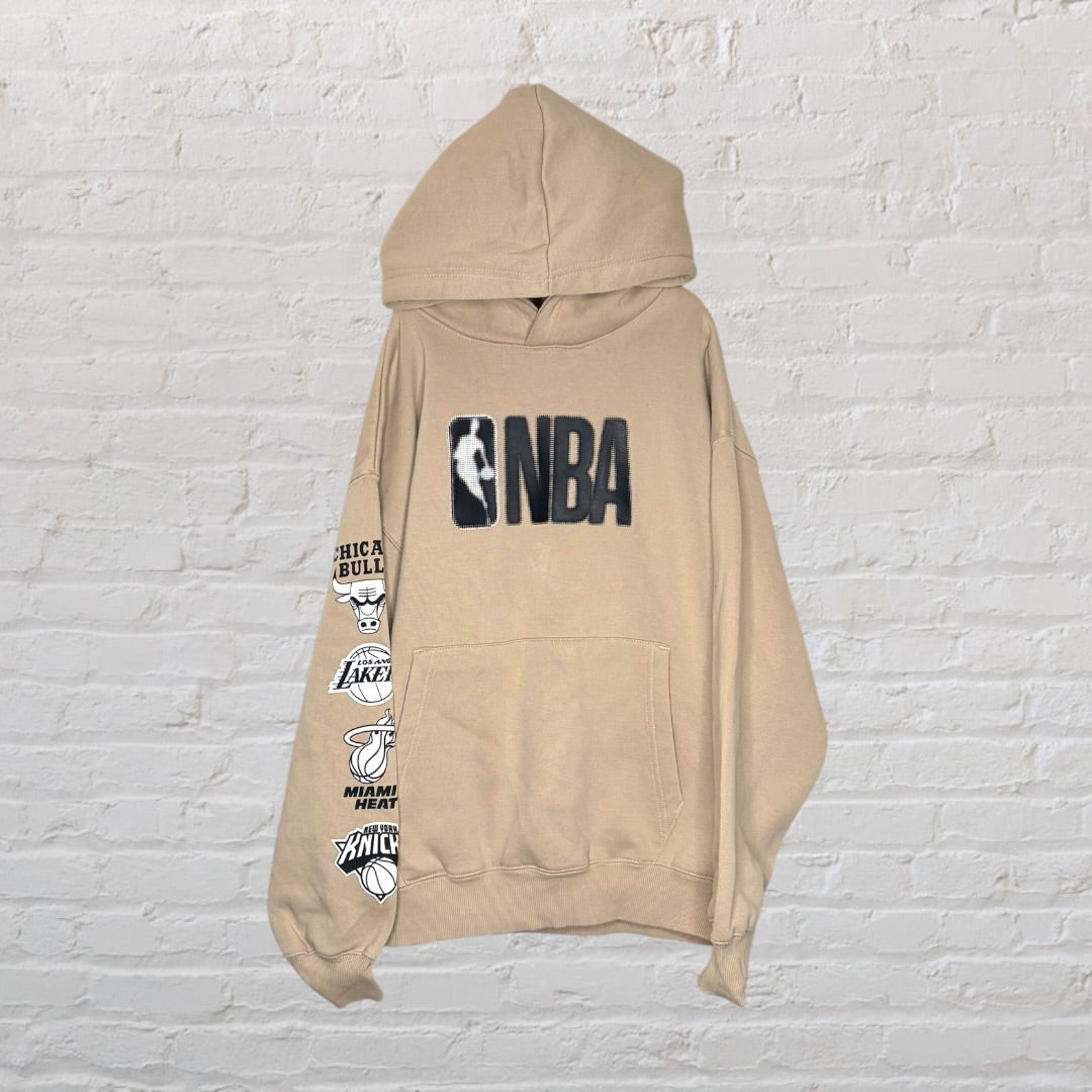 Beige NBA hoodie featuring team logos on the sleeve and NBA logo on the front.