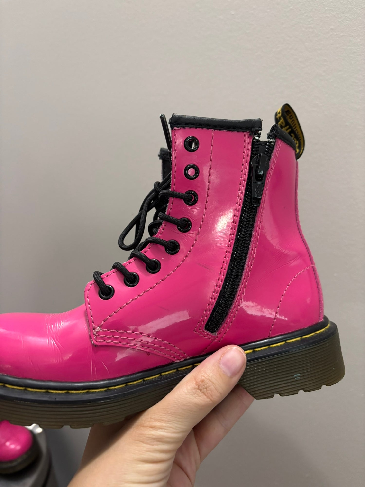 Bright pink lace-up combat boots with black laces and soles, featuring a pull tab at the back.