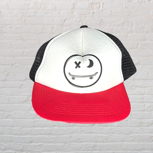 Trucker hat with a white front panel featuring a skater emoji graphic, red brim, and black mesh back.