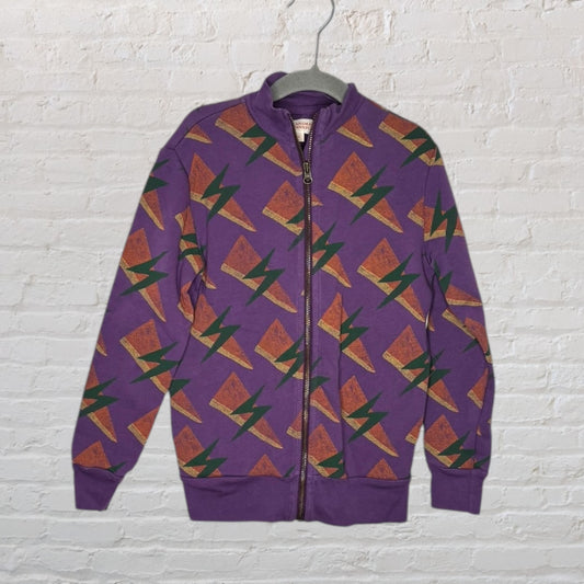Purple zip-up jacket with a geometric pattern in orange and green, hanging on a hanger against a white brick background.
