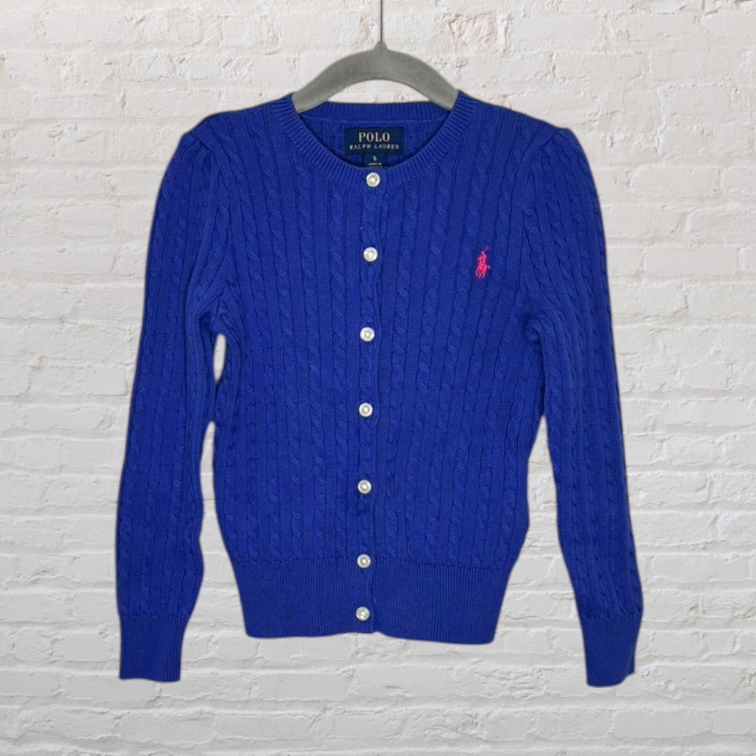 Blue cable knit cardigan with buttons and pink Polo Ralph Lauren logo, hanging on a hanger.