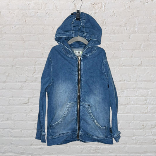 Blue denim hooded jacket with a front zipper and pockets, displayed on a hanger against a brick wall.
