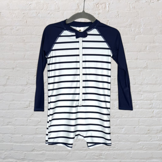 Navy and white striped long sleeve swimsuit with zipper front and solid navy sleeves hanging on a hanger.