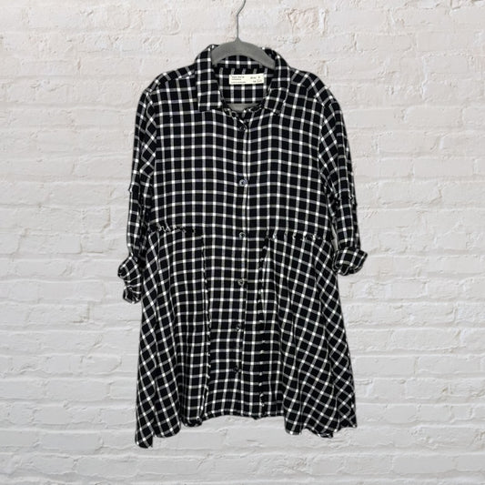 Black and white plaid dress with long sleeves, button-down style, hanging on a hanger.