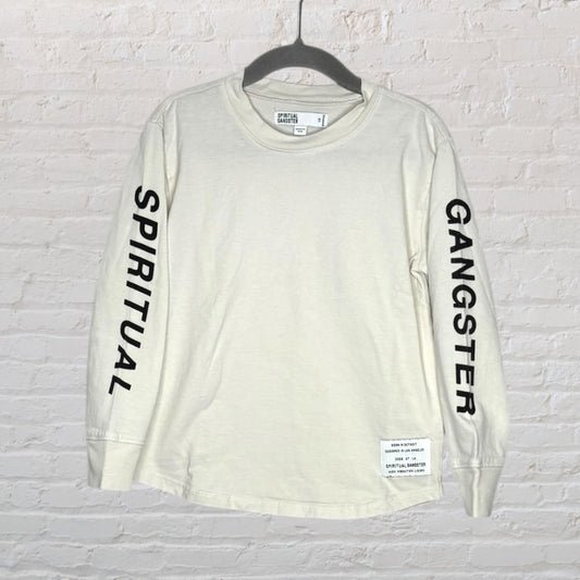 Cream long sleeve tee with 'Spiritual' on one sleeve and 'Gangster' on the other, displayed on a hanger against a brick wall.