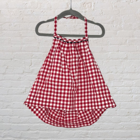 Red and white gingham apron style dress with spaghetti straps, hung on a hanger.