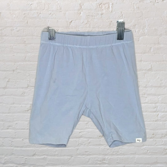 Light blue unisex shorts on hangers against a brick wall background.