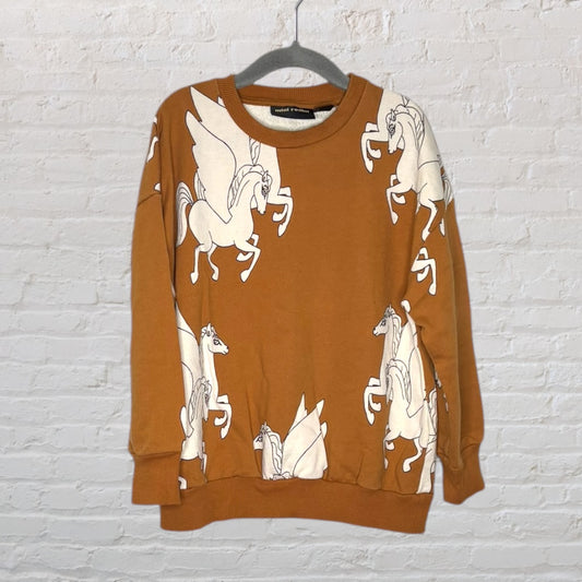 Brown sweatshirt with white Pegasus graphics, brand Mini Rodini, hanging on a hanger against a brick wall.