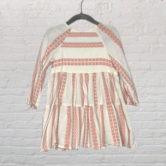 Long sleeve dress with pink and white geometric patterns, featuring ruffled tiers, displayed on a hanger.