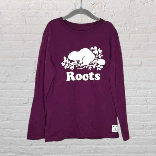 Purple long sleeve T-shirt with a white Roots beaver logo on the front, hanging on a hanger.