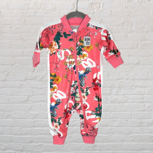 Pink floral Bonds baby onesie with zipper, featuring colorful flowers and birds, displayed on a hanger.