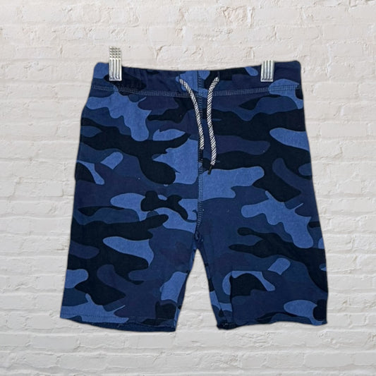 Blue and black camouflage patterned drawstring shorts hanging on white background.