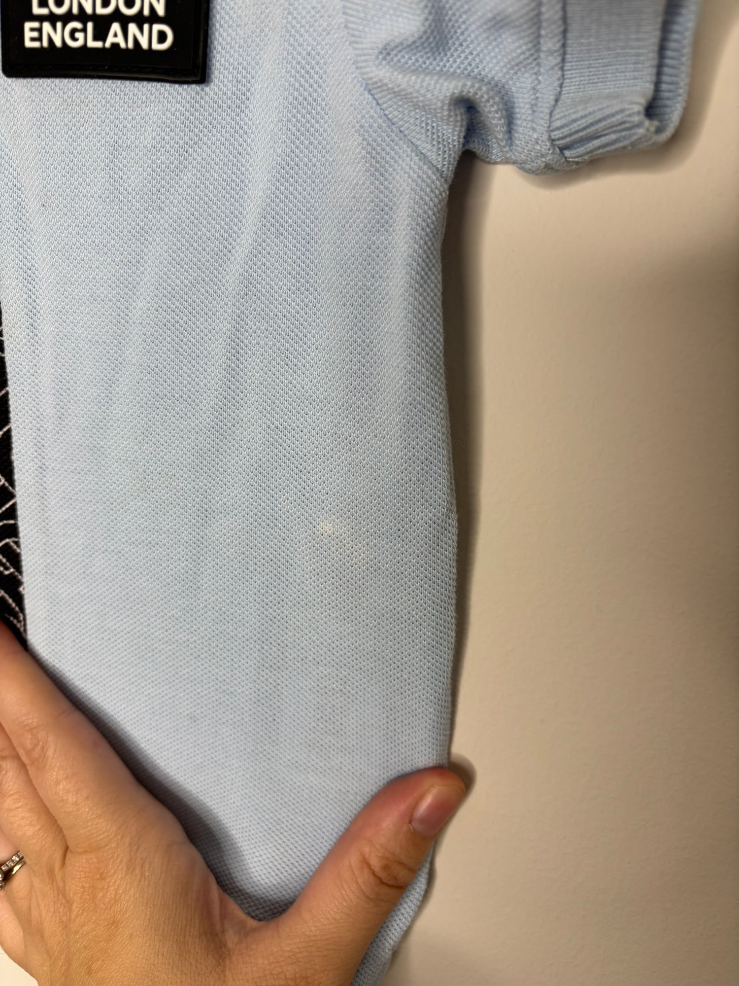 Light blue Burberry London polo shirt with black and white pattern strip and brand logo on the front.