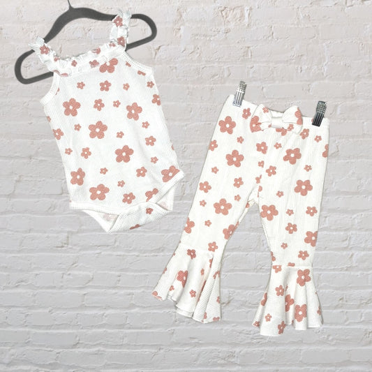 A white baby onesie and matching bell bottom pants set with brown floral print and ruffle details.