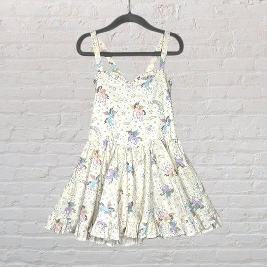 A sleeveless dress with a whimsical print of unicorns and rainbows on a white background, featuring a flared skirt and straps, displayed on a hanger.