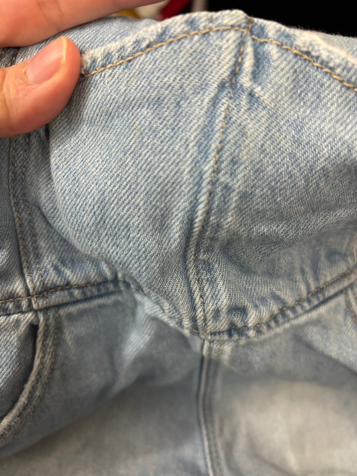 Light blue denim overalls shorts with adjustable straps and pockets, hanging on a hanger.