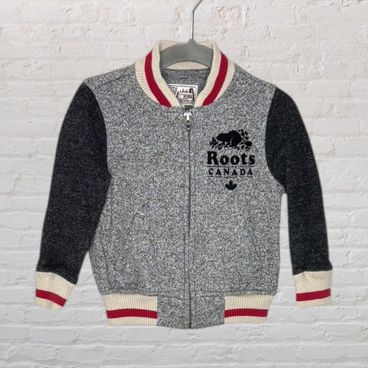Roots Canada gray and black zip-up sweater with red and white striped cuffs and collar on a hanger.