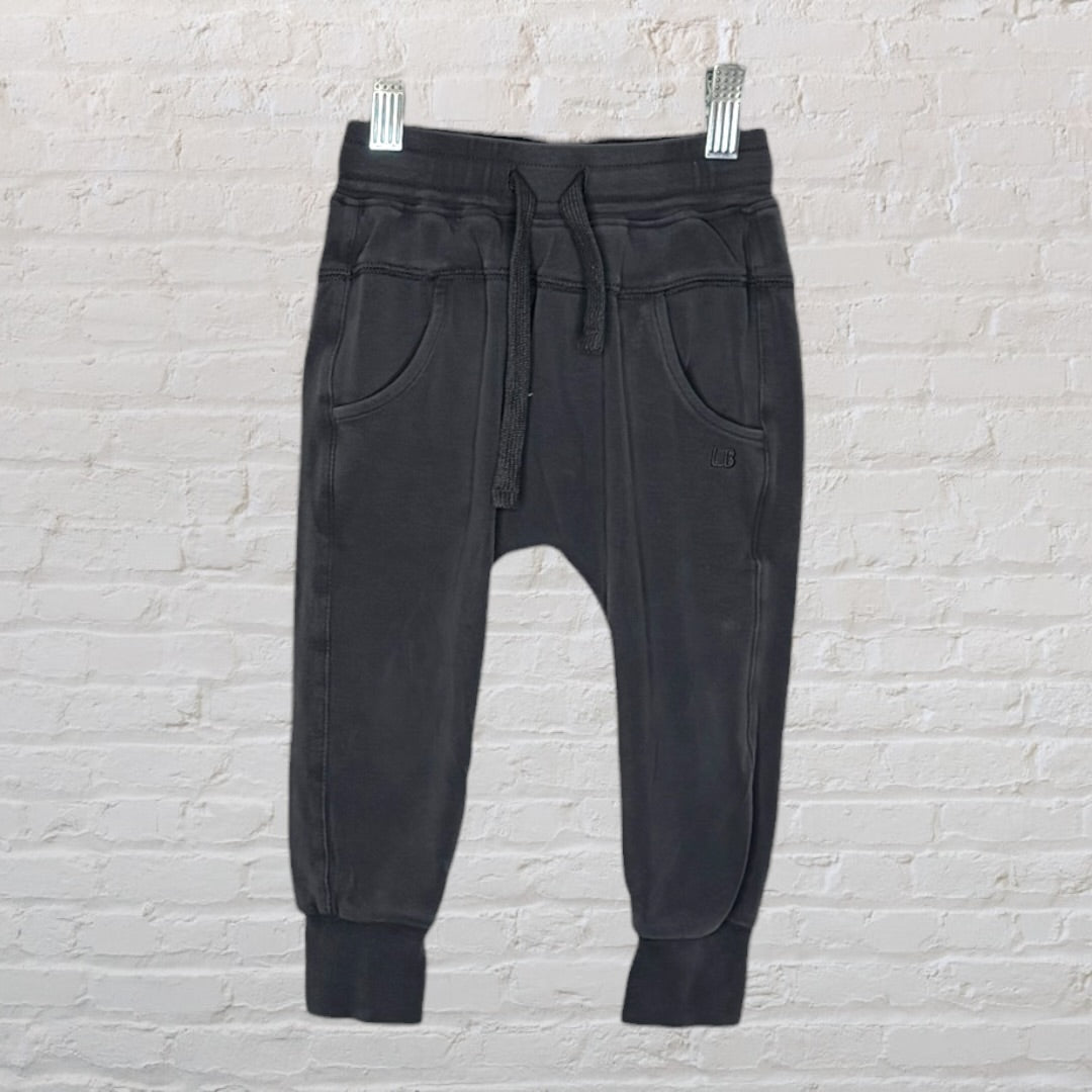 Black lounge set with a long-sleeve top featuring a front pocket and matching pants hanging on a hanger.