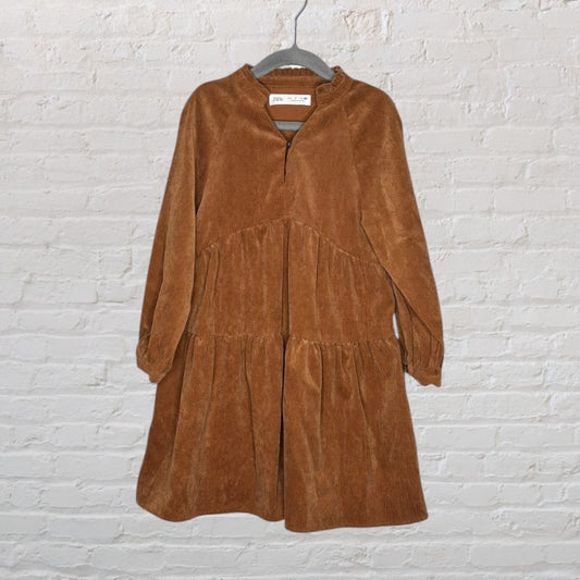 Brown corduroy tiered dress with long sleeves from Zara, displayed on a hanger against a brick wall.