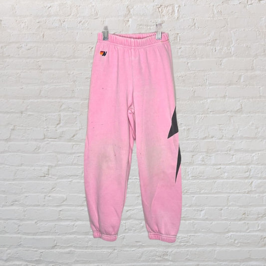 Pink jogger sweatpants with elastic waistband and cuffs, featuring a black graphic on the leg.