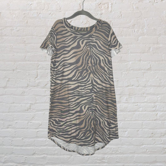 Women's zebra print t-shirt dress in beige and black, with short sleeves and a relaxed fit, hanging on a black hanger.